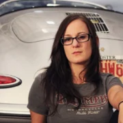 Sarah Lateiner standing confidently in an automotive garage, symbolizing her leadership as a trailblazing female mechanic and educator.
