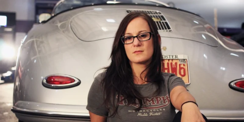 Sarah Lateiner standing confidently in an automotive garage, symbolizing her leadership as a trailblazing female mechanic and educator.