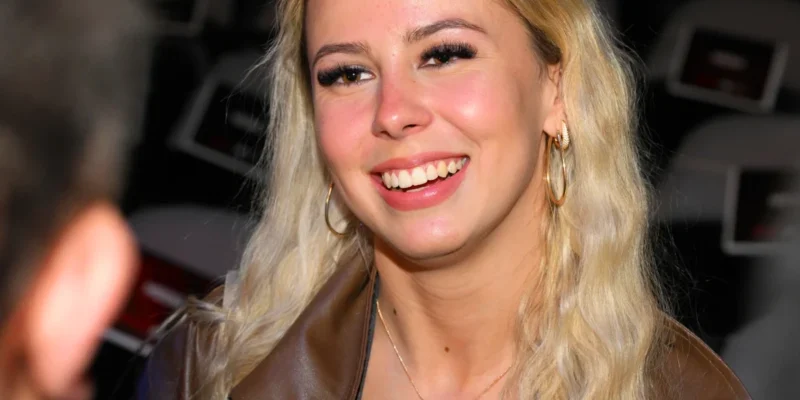 Hailey Welch smiling at a public event in 2025. The viral "Hawk Tuah Girl" has built a net worth of $500,000 through merchandise, appearances, and media ventures.