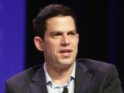 Jeffrey Marty speaking at a public event in a dark suit, representing his legal and media career.