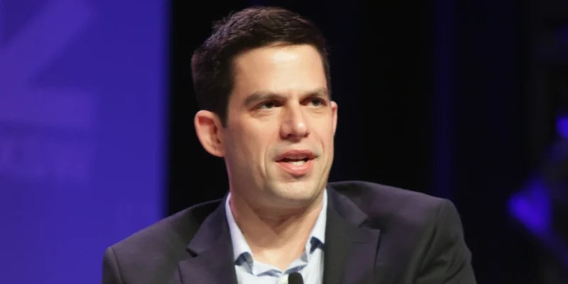 Jeffrey Marty speaking at a public event in a dark suit, representing his legal and media career.