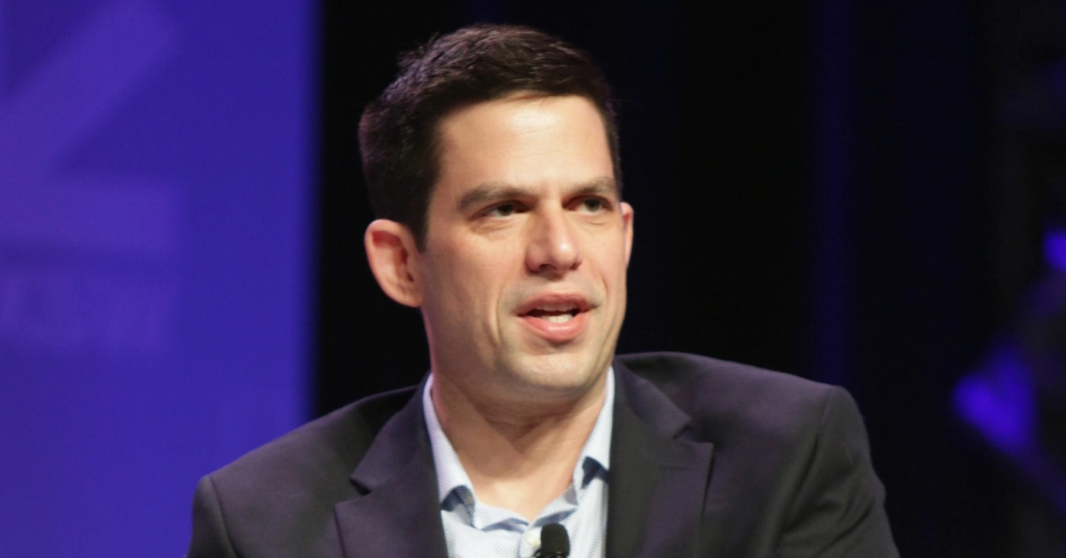 Jeffrey Marty speaking at a public event in a dark suit, representing his legal and media career.