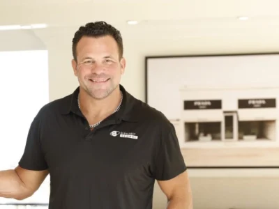 John Cerasani smiling in black Glencrest Global polo shirt in office doorway