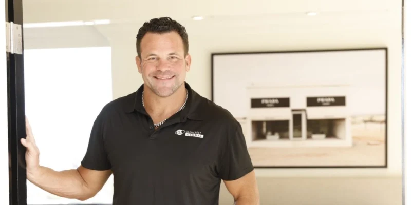 John Cerasani smiling in black Glencrest Global polo shirt in office doorway