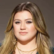 Kelly Clarkson showcasing her confident style with blonde highlights and teal blazer - the multi-platform entertainment mogul continues to redefine celebrity success in 2025