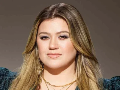 Kelly Clarkson showcasing her confident style with blonde highlights and teal blazer - the multi-platform entertainment mogul continues to redefine celebrity success in 2025