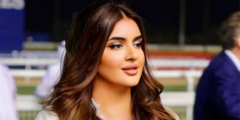 Princess Kazer at royal event wearing elegant white outfit with diamond necklace and styled brown hair