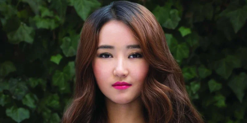 Yeonmi Park Net Worth: Yeonmi Park smiling confidently outdoors, symbolizing her inspiring journey and financial achievements.