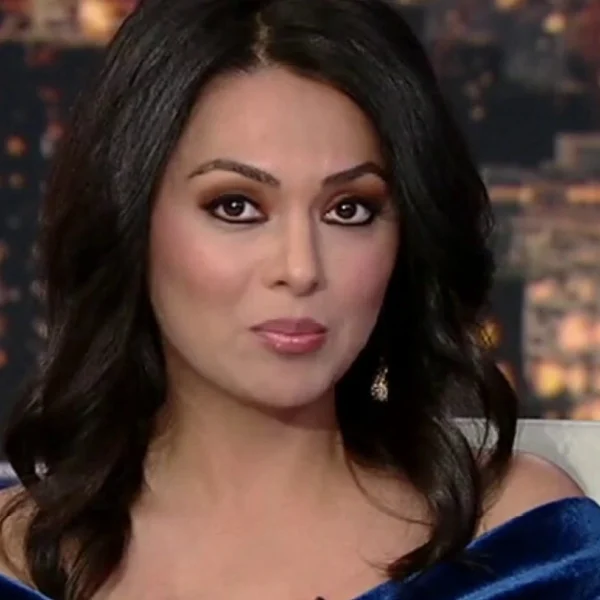 Aisha Hosny on set in a blue dress, confidently presenting live news, reflecting her growing influence in 2025 media.