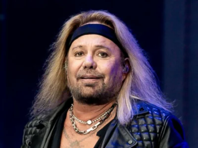 Vince Neil performing live on stage with signature blonde hair and leather jacket, showcasing the Mötley Crüe frontman's iconic rock star presence before his 2025 health challenges